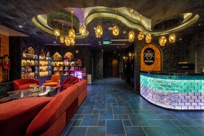 A hotel lobby with a seating area, a bar, and a reception desk.