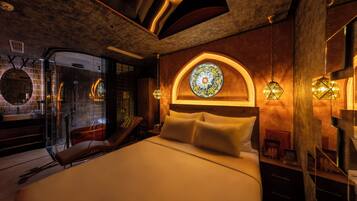 Ein modernes Schlafzimmer mit einem großen Bett, einer gläsernen Duschkabine und einem dekorativen Buntglasfenster.