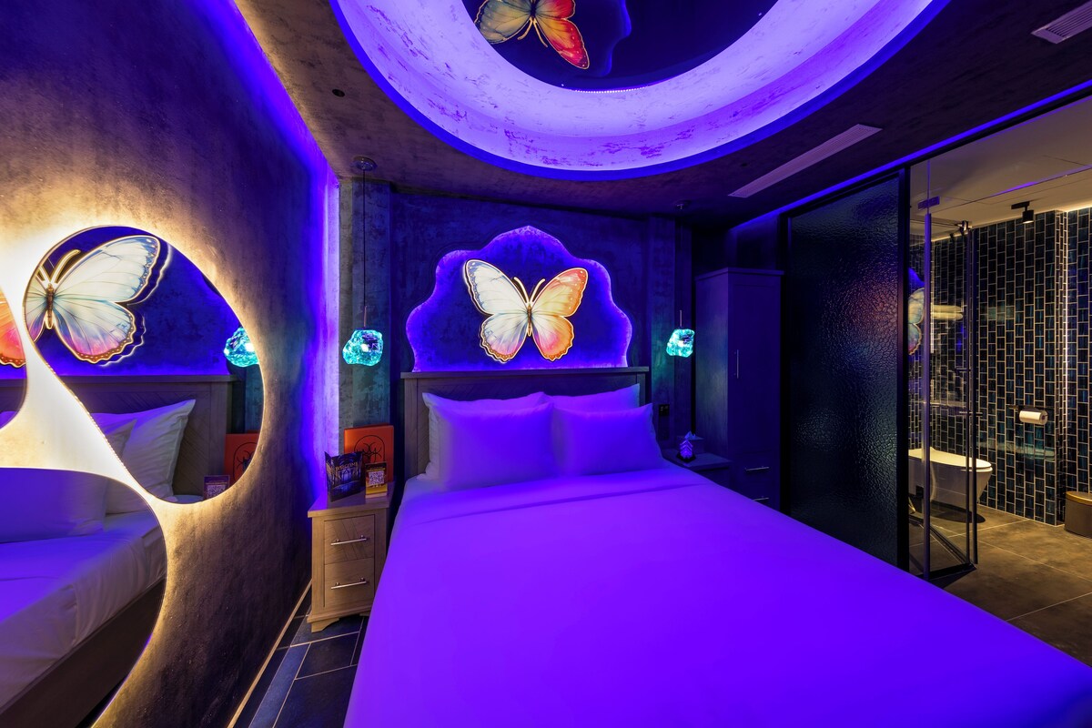 A modern bedroom with a curved ceiling, butterfly wall art, and a glass shower enclosure.