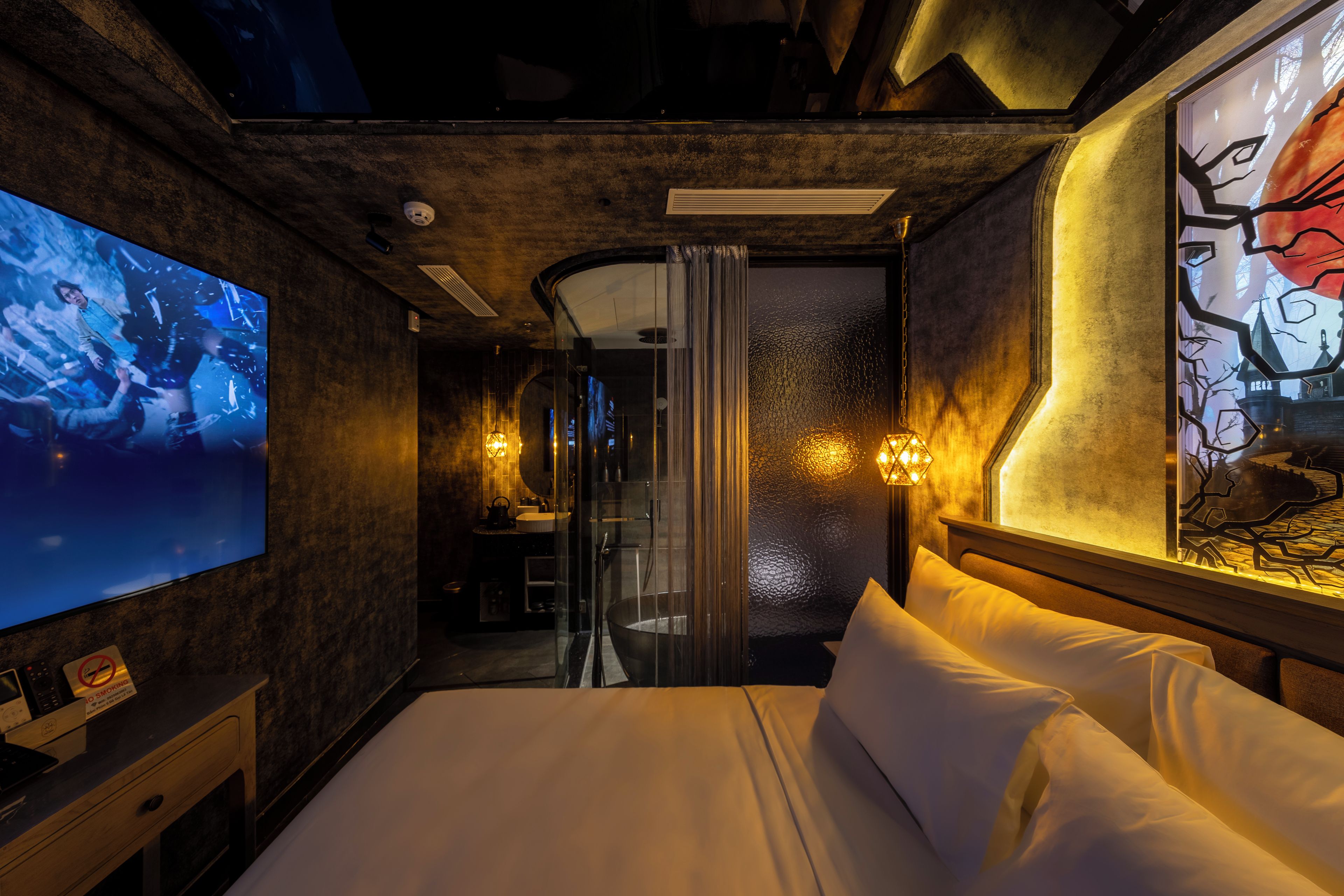 A hotel room with a large bed, a TV, a bathroom with a glass door, and a painting on the wall.