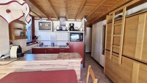 A compact kitchen with wooden cabinets, a built-in microwave, and a red countertop. - Jatoba - apartment - 4 people - ski-in/ski-out (Les Gets)
