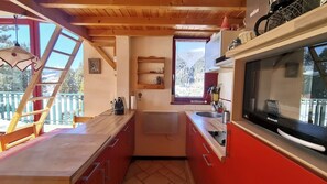 A compact kitchen with a wooden ceiling, a built-in microwave, and a window with a mountain view. - Jatoba - apartment - 4 people - ski-in/ski-out (Les Gets)