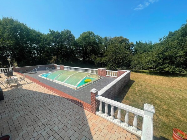 A rooftop pool with a sunshade, surrounded by a brick wall and a white balustrade.