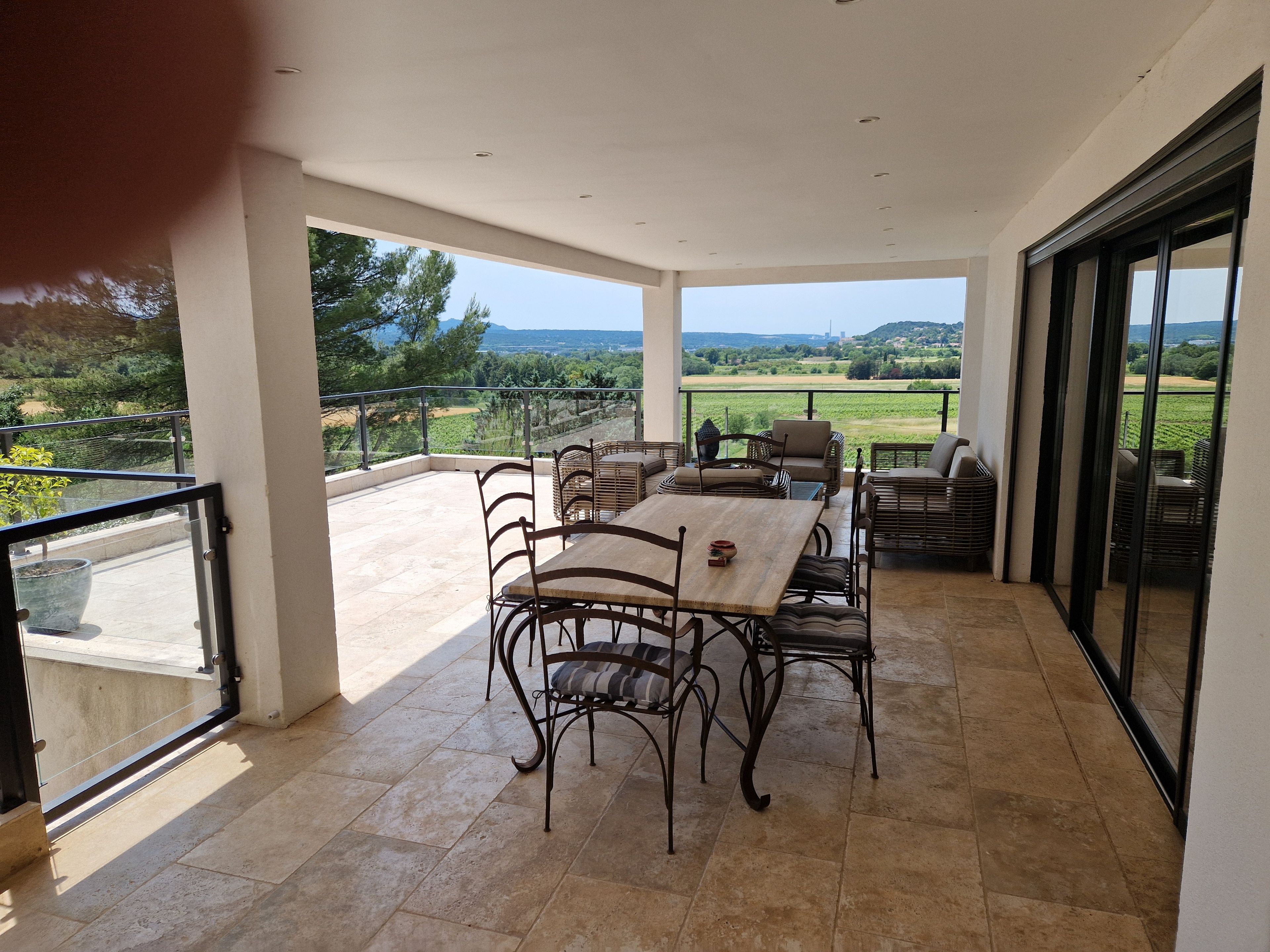 Varanda ampla com mesa e cadeiras, com vista para uma paisagem deslumbrante.