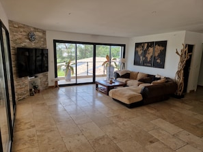 A spacious living room with a large flat-screen TV, a sectional sofa, a coffee table, and a fireplace.