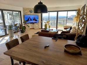 A modern living room with a large TV, a dining table, and a sofa.