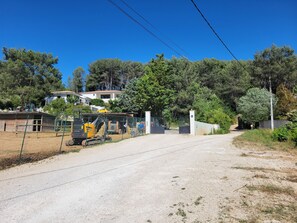 Un camino de grava que conduce a una zona cerrada con maquinaria de construcción y una cerca.