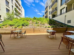 Un patio al aire libre con suelo de madera, mesas y sillas.