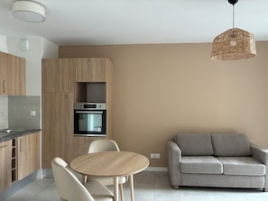 Una cocina moderna con armarios de madera, horno empotrado y una mesa redonda con sillas.
