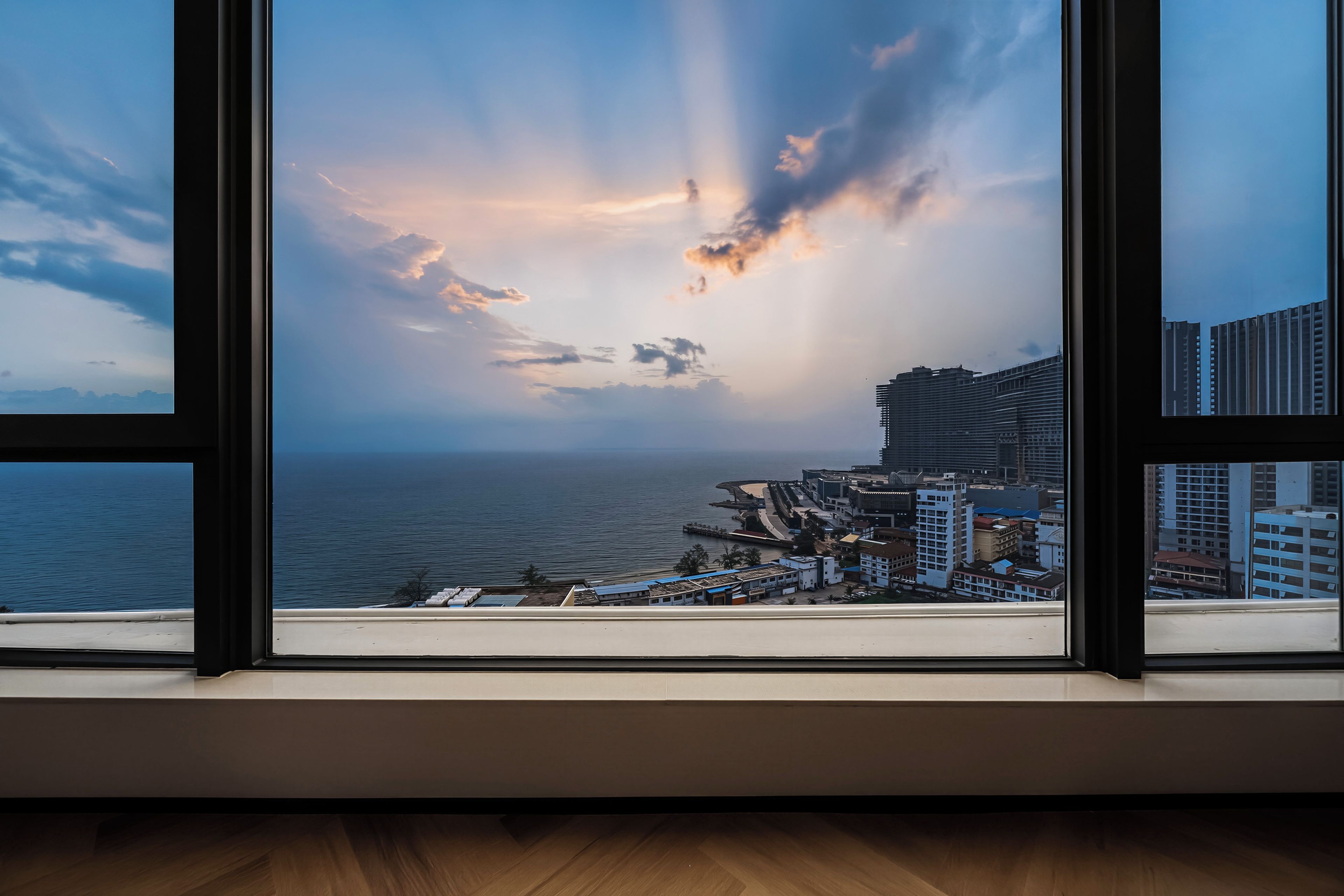 A view through a window of a coastal cityscape with buildings and a body of water.