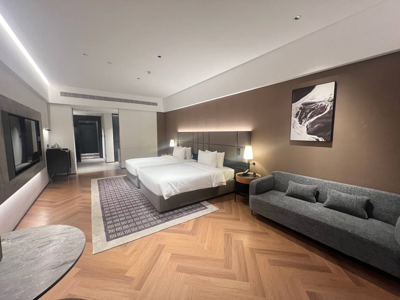 Habitació d'hotel moderna amb un llit gran, un sofà, escriptori i televisió de pantalla plana.