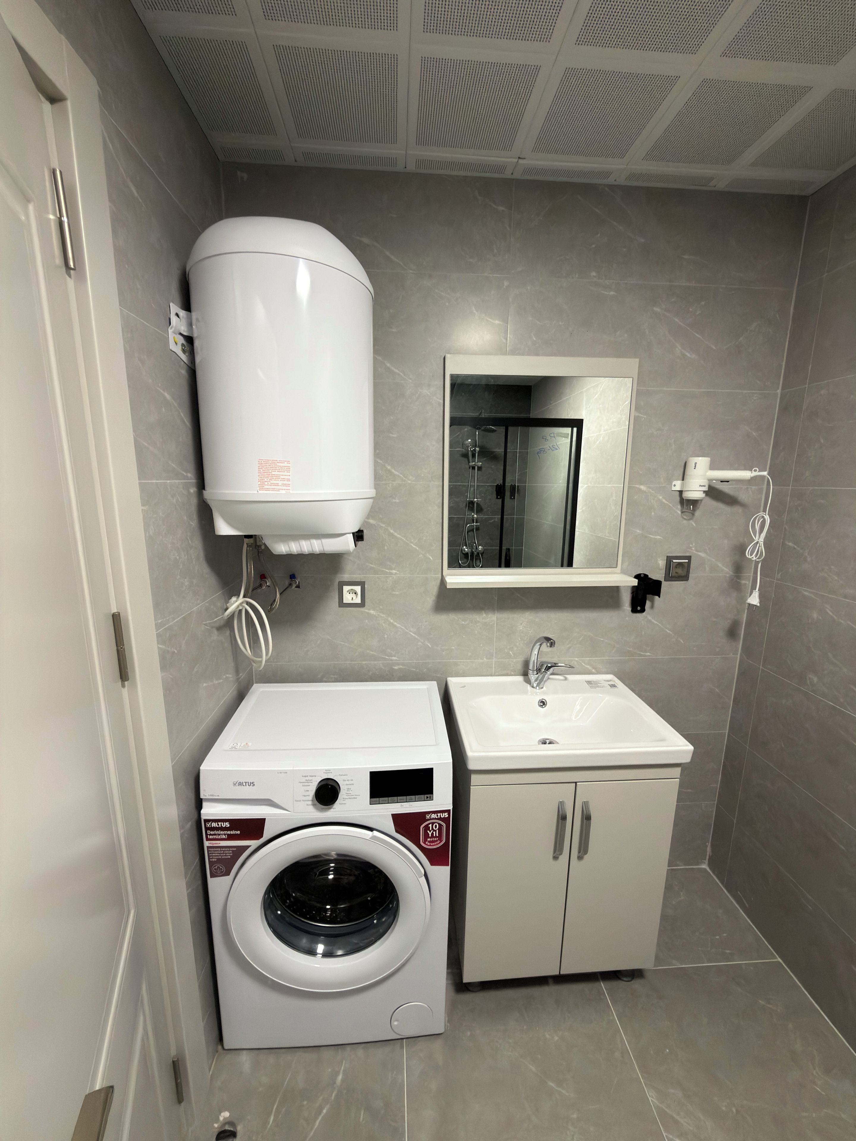 Un baño pequeño con lavadora integrada, inodoro y lavamanos.