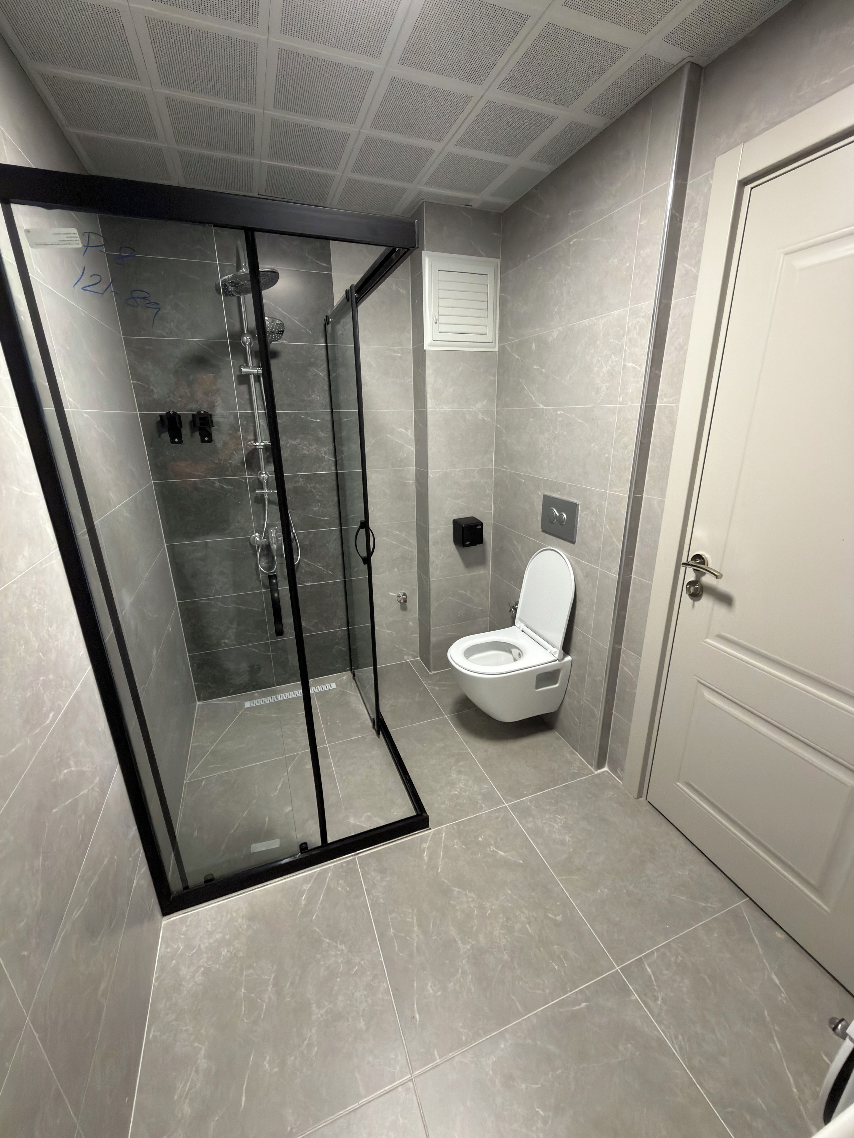 Un baño moderno con ducha envuelta en vidrio, inodoro y puerta.