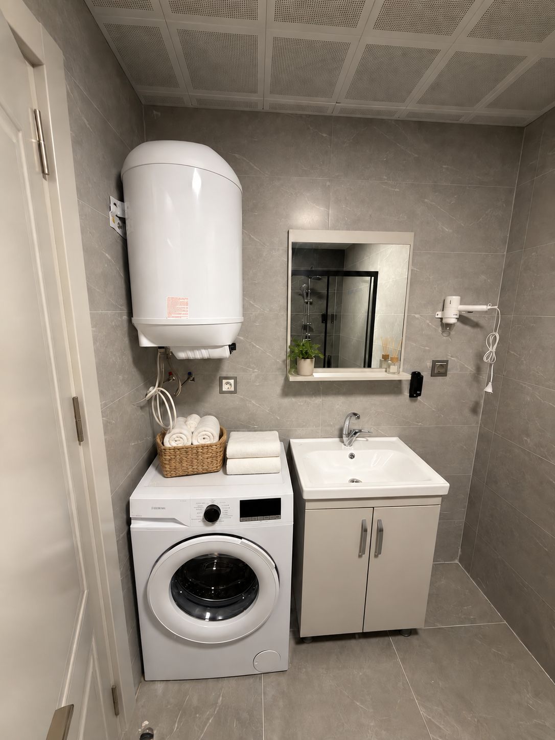 A compact bathroom with a built-in washing machine, a sink, and a towel rack.