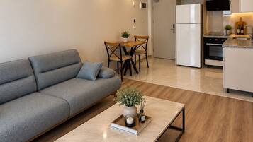 A modern living room with a sofa, a coffee table, and a dining area with a table and chairs.