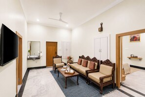 A modern living room with a flat-screen TV, a sofa set, a coffee table, and a ceiling fan. - Alaya Stays Aira Amar Villa 3BHK (Udaipur)