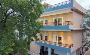 A multi-story residential building with balconies, a staircase, and a tree in the foreground. - Alaya Stays Aira Amar Villa 3BHK (Udaipur)