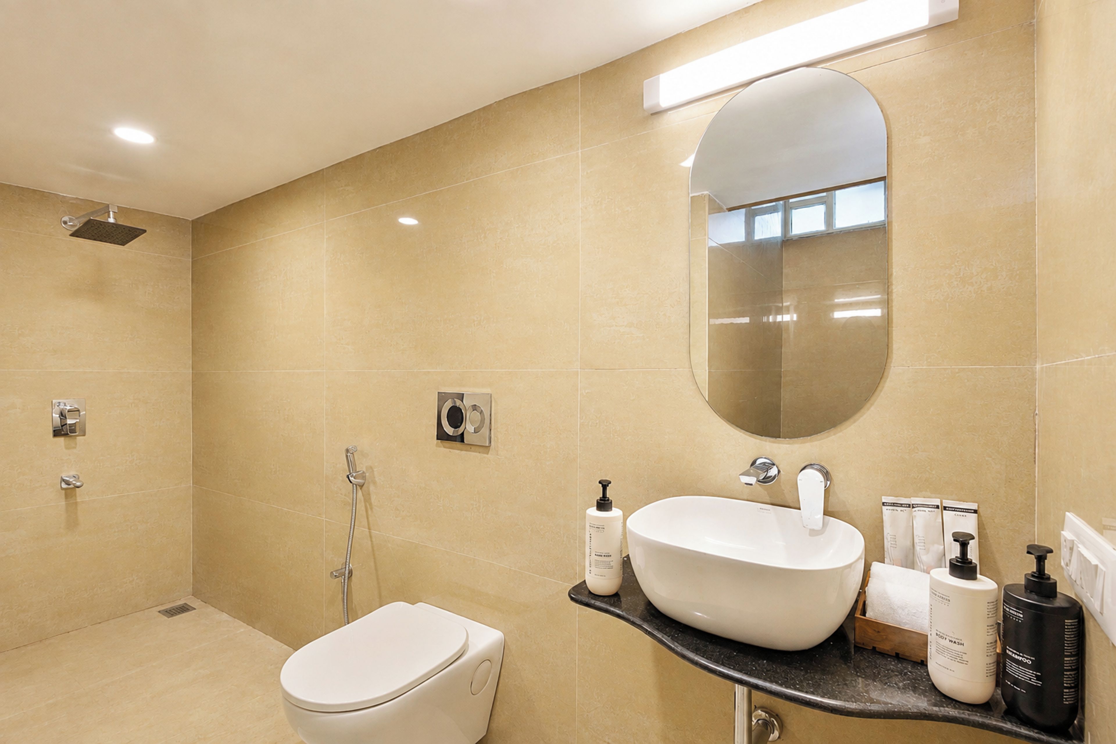 A modern bathroom with a toilet, bidet, and a large mirror above the sink.