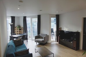 Ein modernes Wohnzimmer mit einer Couch, einem Couchtisch, einem Fernseher und einem Essbereich mit Tisch und Stühlen.