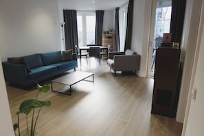 Ein modernes Wohnzimmer mit Sofa, Couchtisch und Essbereich.