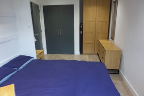 Ein Schlafzimmer mit Bett, Kleiderschrank, Schminktisch und Spiegel.