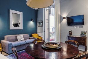 A modern living room with a sofa, a dining table, and a TV mounted on the wall. - Charming Apartment on the Rome Terrace Near the Pantheon (Roma)