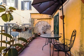 An outdoor patio with a round table and chairs, potted plants, and a brick wall. - Charming Apartment on the Rome Terrace Near the Pantheon (Roma)