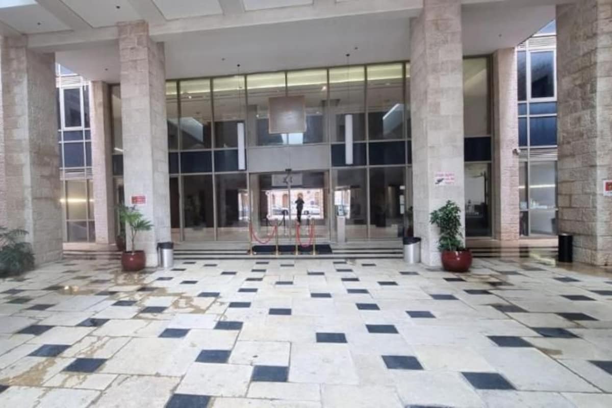 A spacious lobby with a checkered floor, large glass doors, and stone pillars.