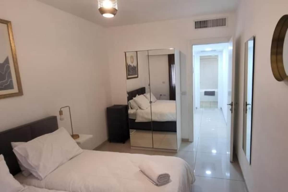 A bedroom with a bed, bedside table, and a mirror.