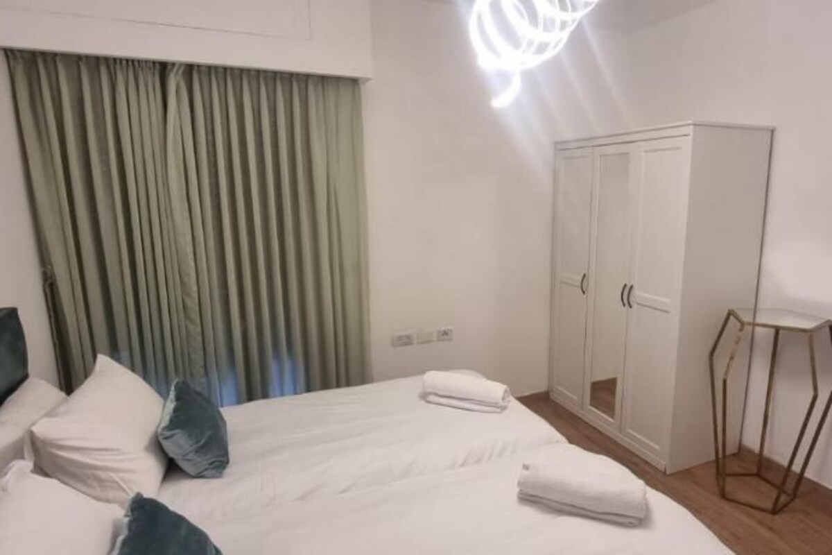 A hotel room with a bed, a wardrobe, a standing lamp, and a view through a door.