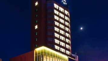 Een meerlaags hotel met een opvallend ATOUR HOTEL bord, een zichtbaar logo en een goed verlichte gevel.