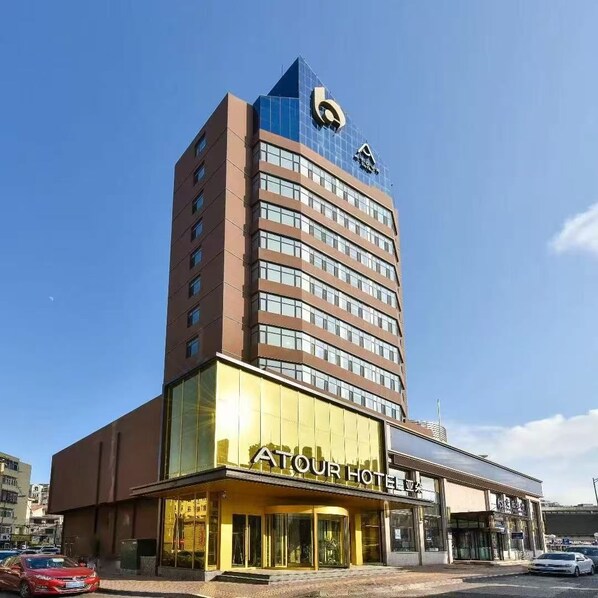 A hotel with a prominent 'A' logo on the top, a large glass facade, and a sign reading 'ATOUR HOTEL'.