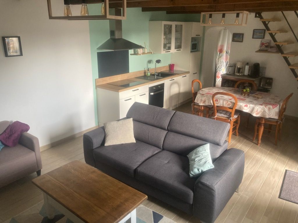 A living room with a sofa, a coffee table, and a dining area with a table and chairs.