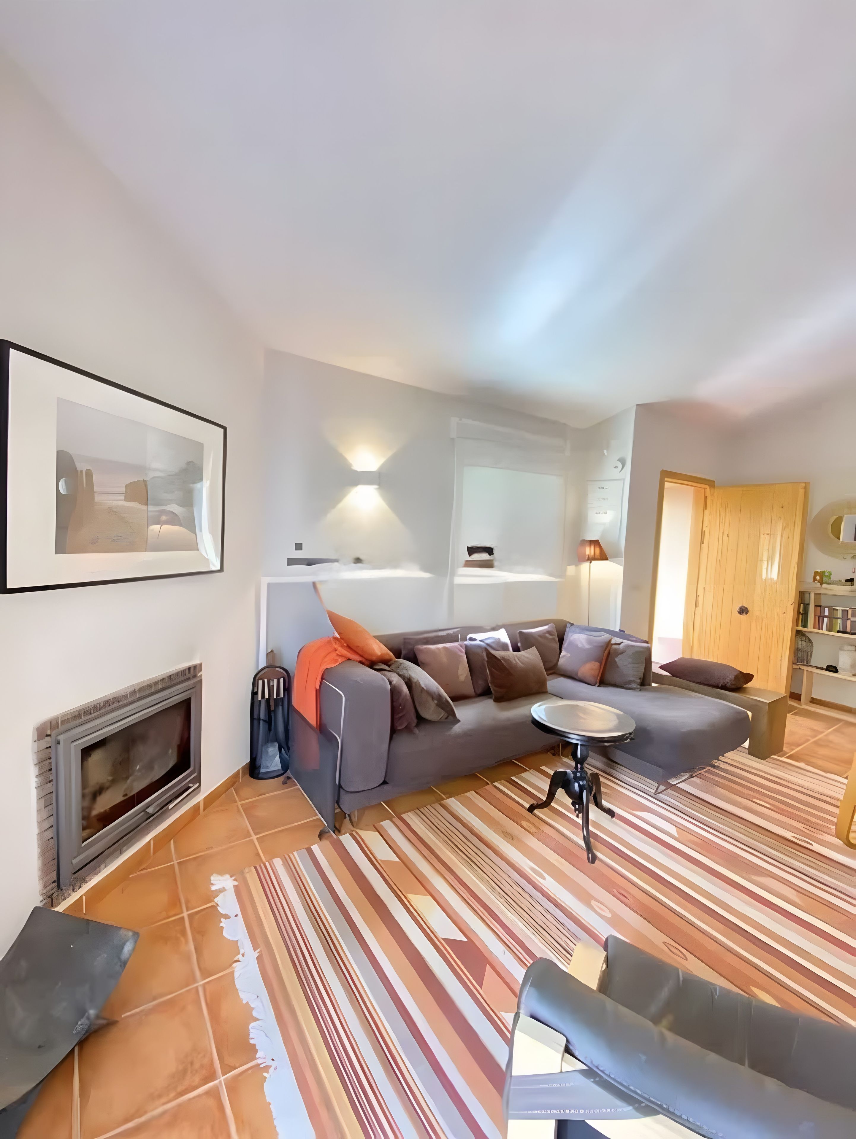 Una sala de estar moderna con chimenea, un sofá, una mesa de centro y un tapete a rayas.