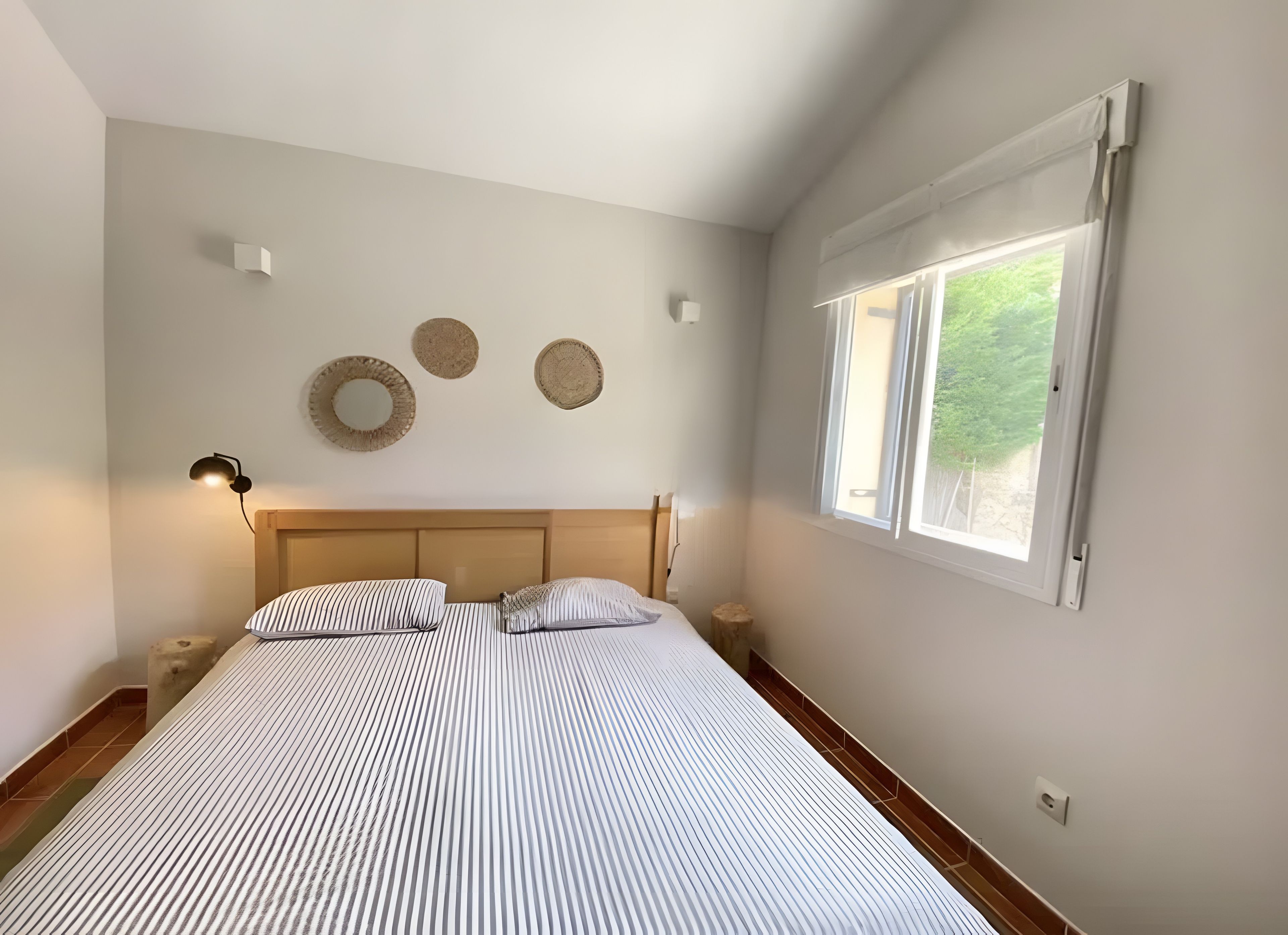 Ein Schlafzimmer mit einem Bett, Nachttischlampen, einem Fenster und Wanddekoration.