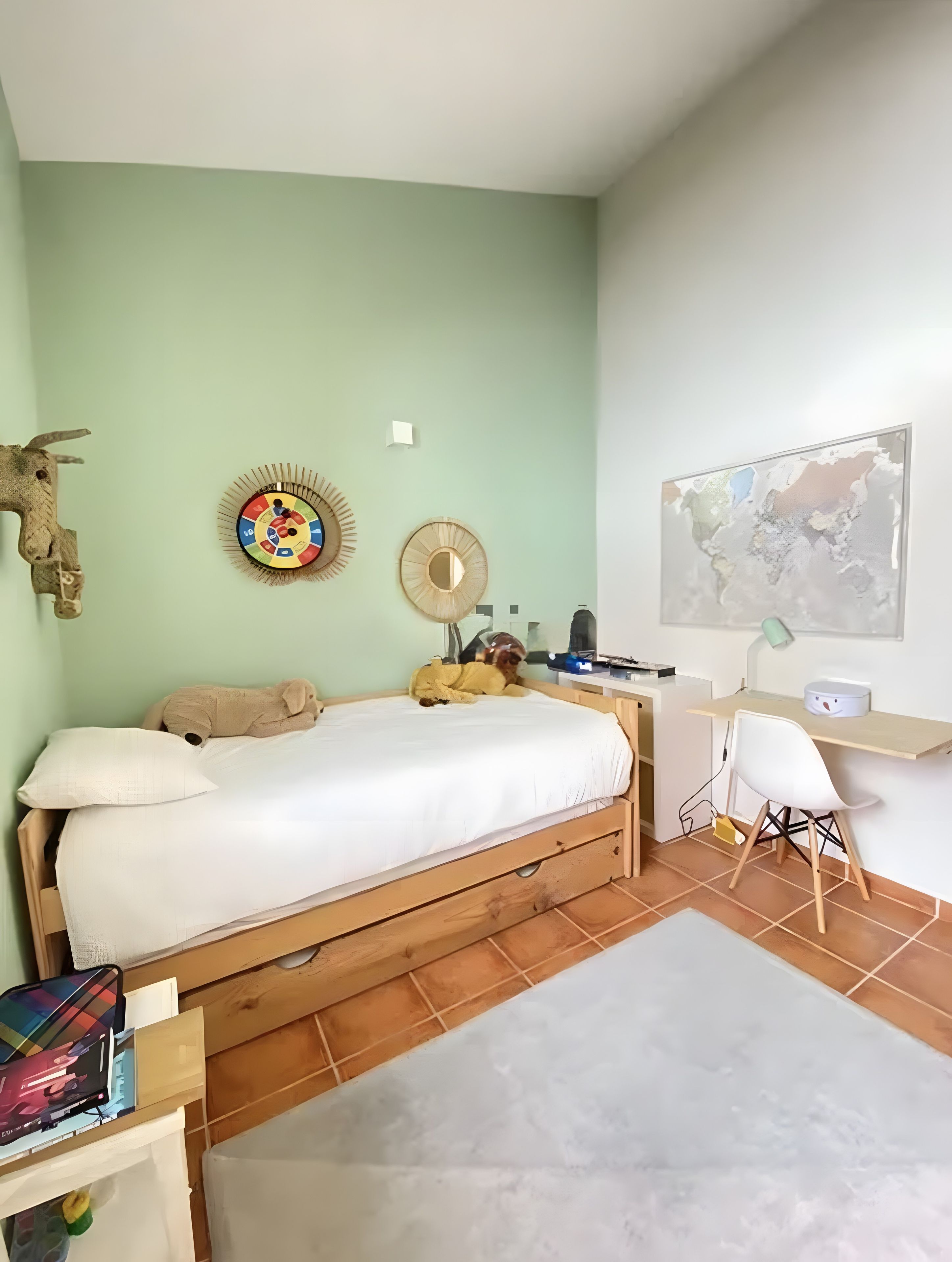 Un dormitorio con cama, escritorio, silla, un mapa en la pared y un adorno decorativo.