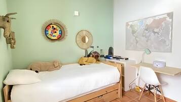 Un dormitorio con cama, escritorio, silla, un mapa en la pared y un adorno decorativo.