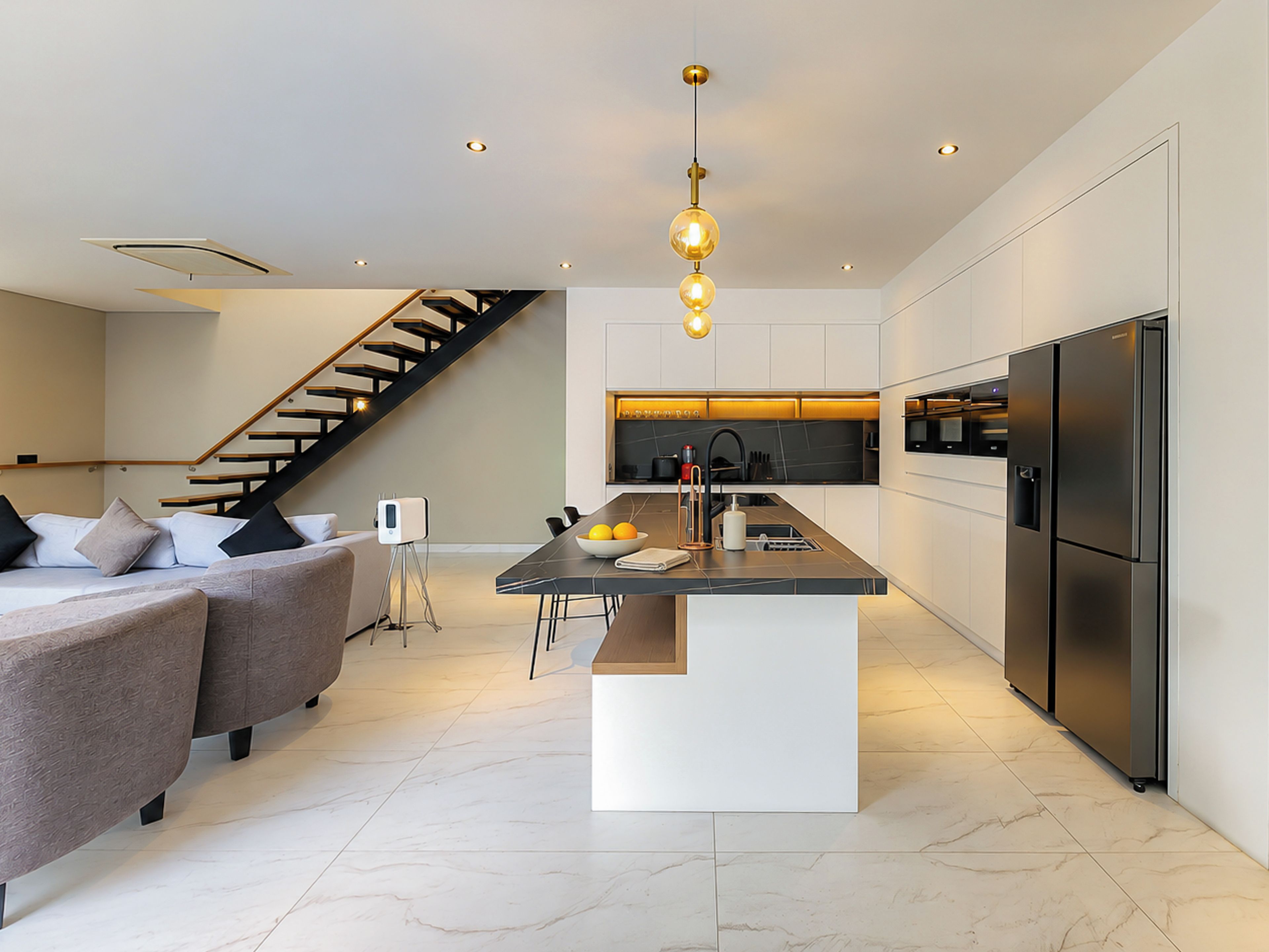 A modern kitchen with a central island, built-in appliances, and a staircase leading to an upper level.