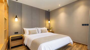 A modern bedroom with a large bed, wooden flooring, and pendant lighting.