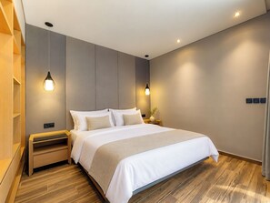 A modern bedroom with a large bed, wooden flooring, and pendant lighting. - Cyrille Villa Jimbaran by Nagisa Bali (Badung)