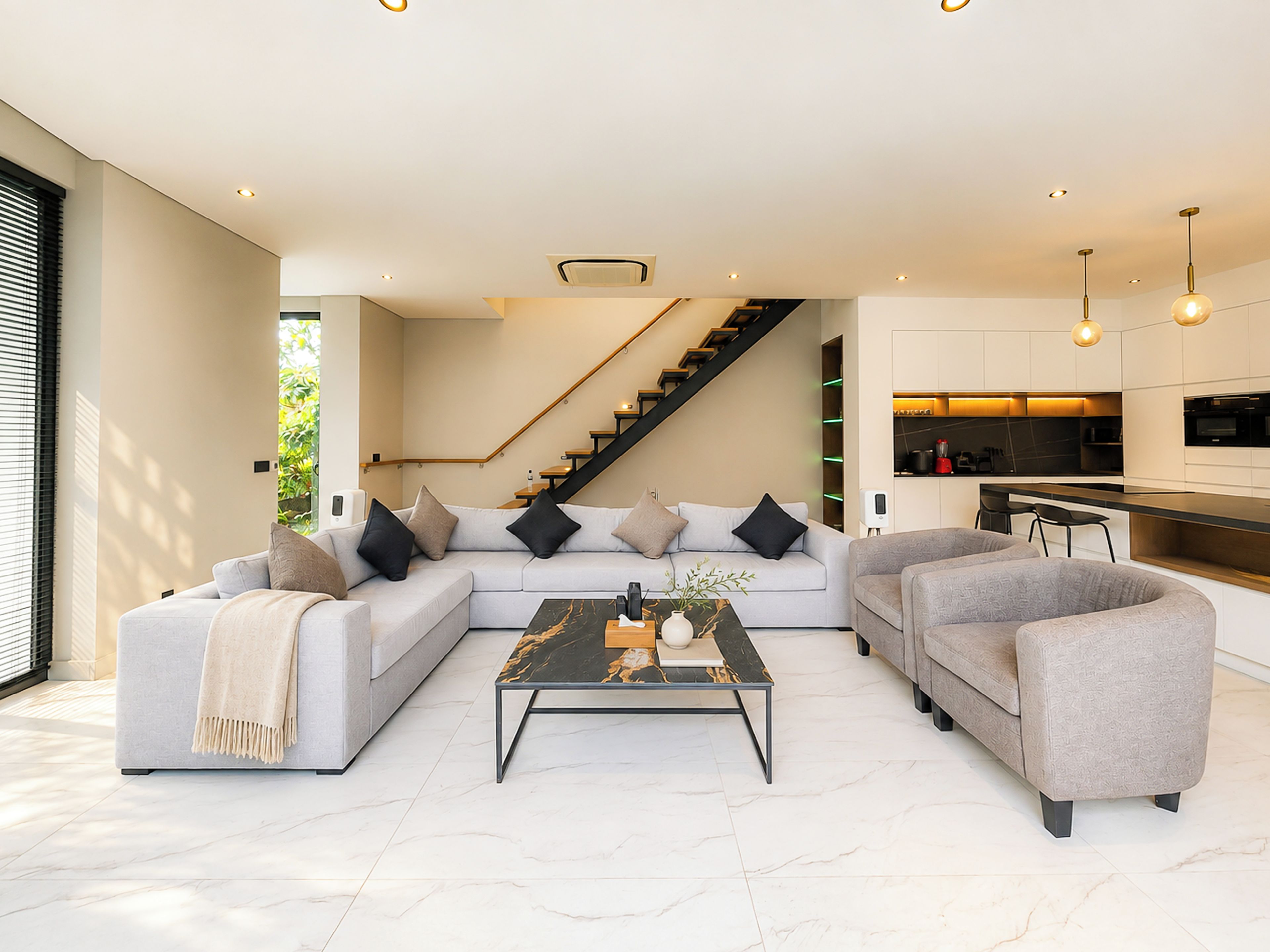 Ein modernes Wohnzimmer mit einer Sofagarnitur, einem Couchtisch und einer Treppe zu einer oberen Ebene.