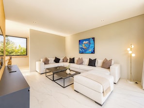 A modern living room with a sectional sofa, a coffee table, and a floor lamp. - Cyrille Villa Jimbaran by Nagisa Bali (Badung)
