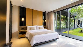 A modern bedroom with a large bed, a wooden headboard, and a view of a garden through floor-to-ceiling windows.