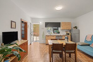 Un espacio habitable compacto con kitchenette, comedor y televisor.