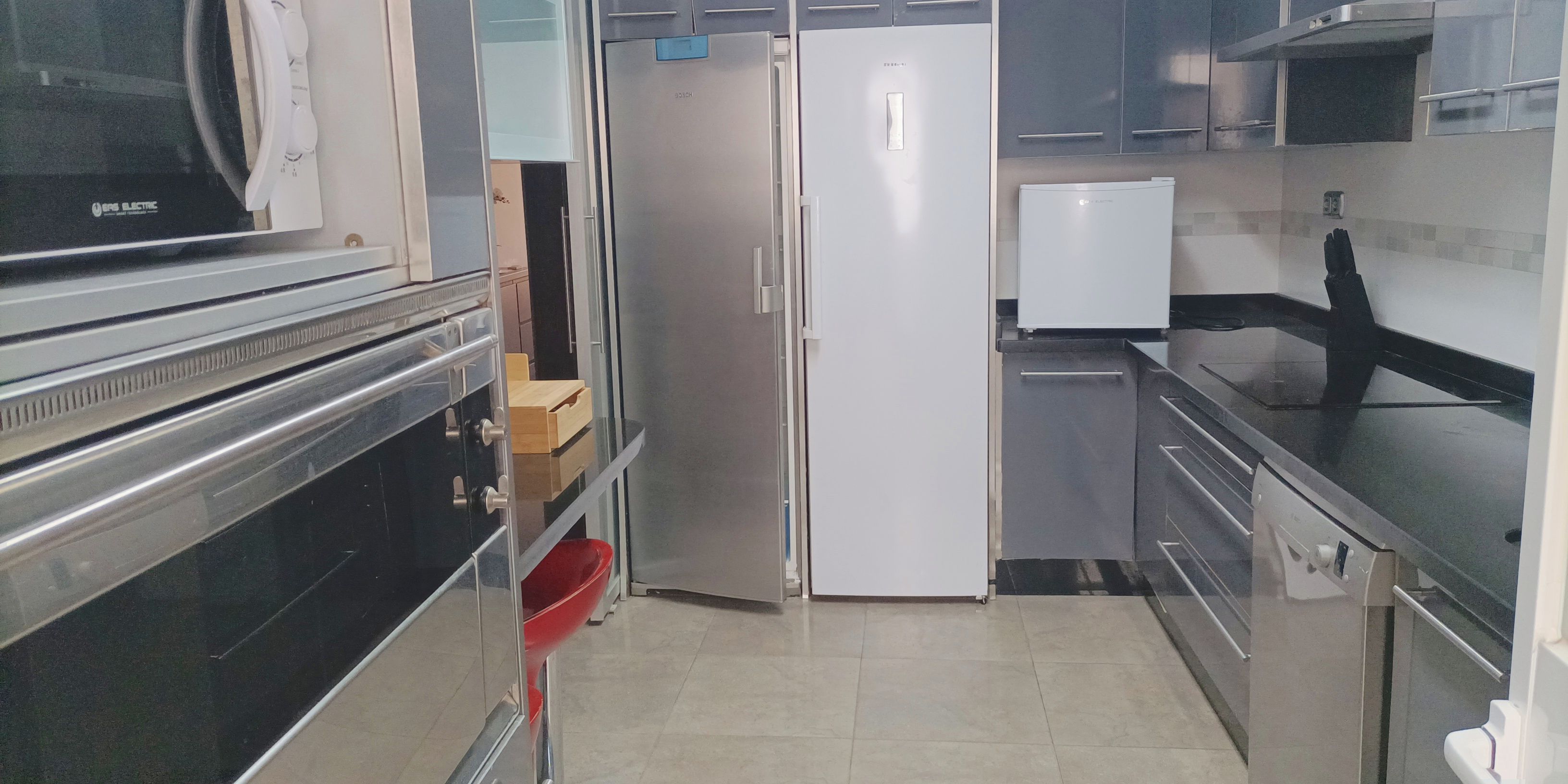 Een moderne keuken met roestvrijstalen apparatuur, een inbouwoven en een koelkast.