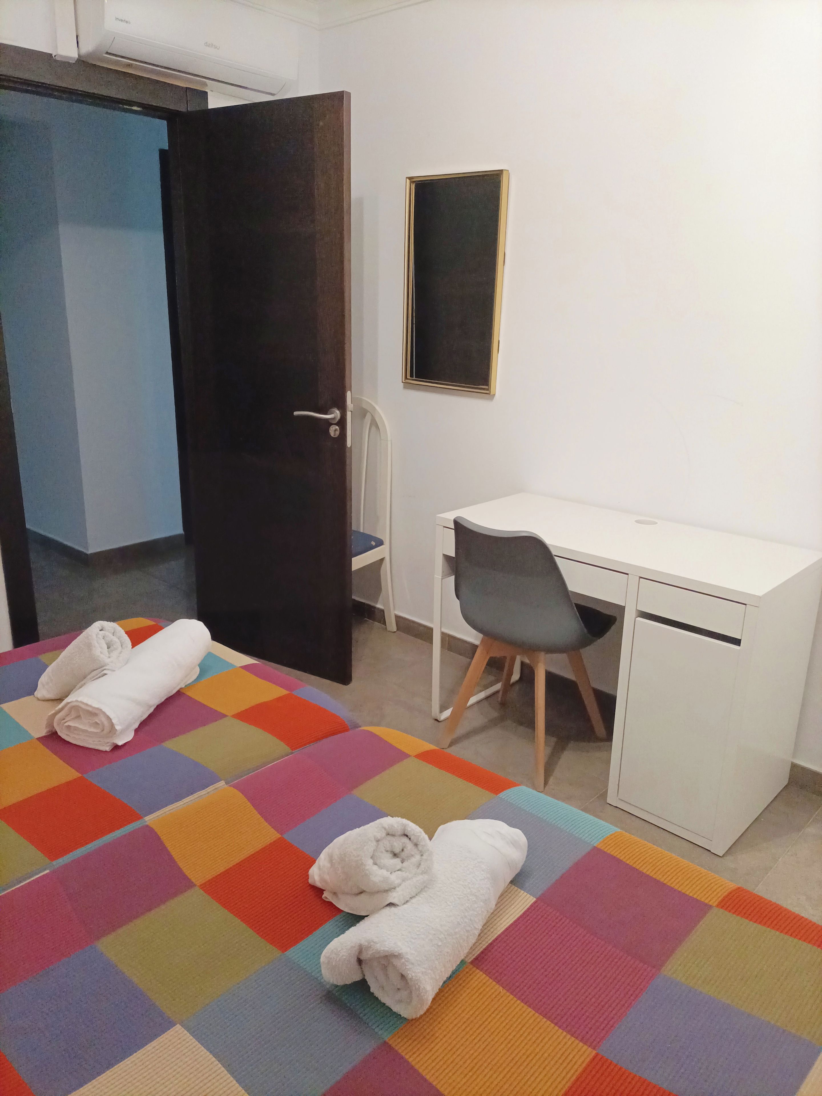 A room with a bed, a desk, a chair, and a door.