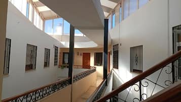 Ein mehrgeschossiges Interieur mit Treppe, Geländern und einem Oberlicht.
