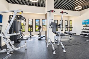 A gym with various exercise equipment, including treadmills and weight machines, and a wall with framed pictures. - Wariruri 214 by Bocobay • Luxury Resort Stay (Noord)