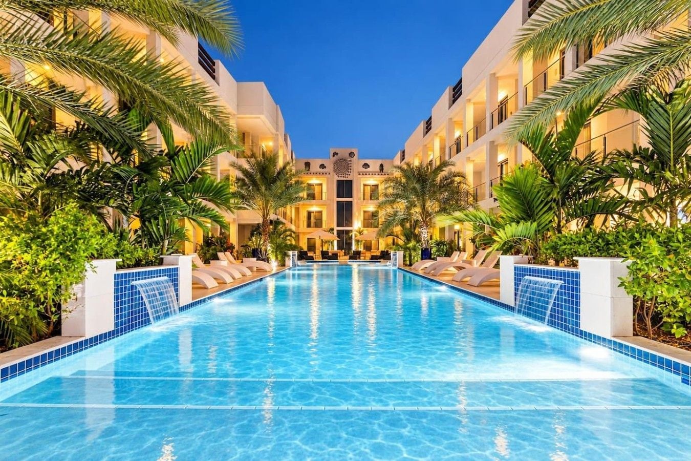 Una piscina de hotel con vistas despejadas a la fachada del edificio, rodeada de exuberante vegetación.