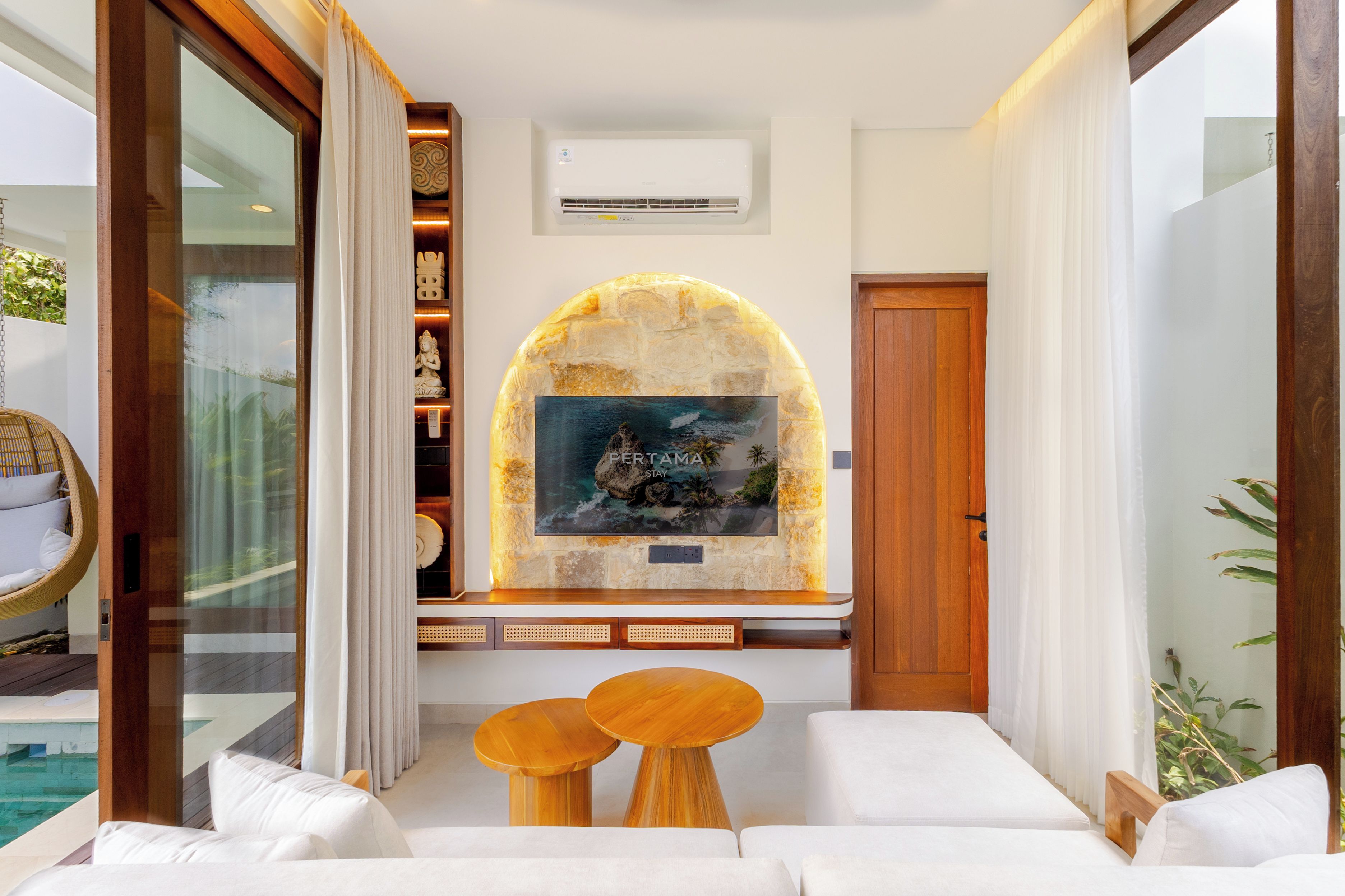 A modern hotel lobby with a stone fireplace, a large framed picture, and a seating area with two wooden tables.